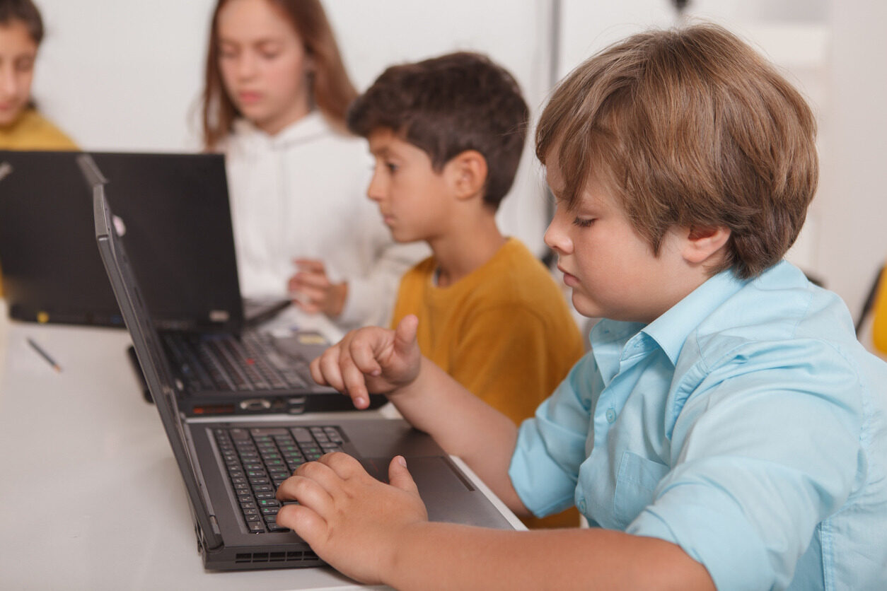 Boy in front of a laptop learning about HTML and CSS in a programming class for children