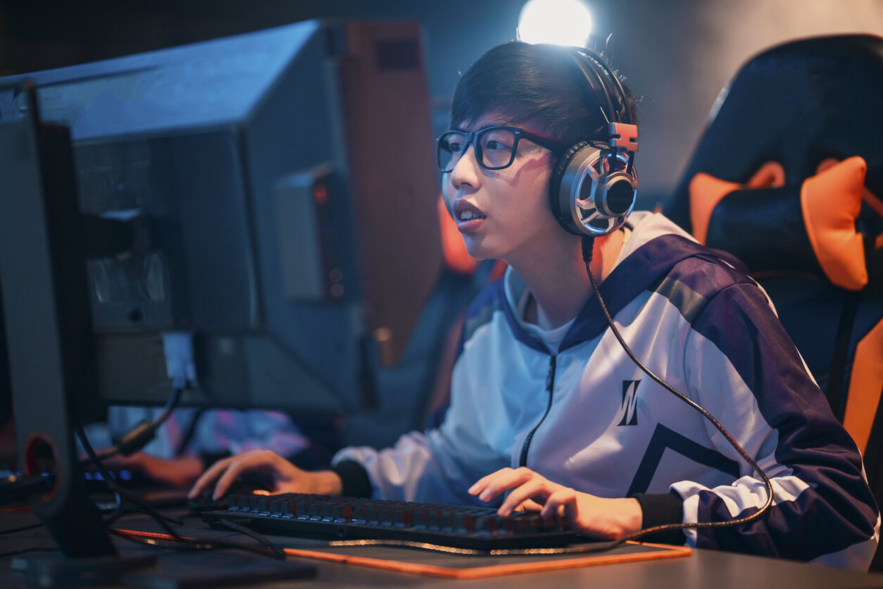 Boy with headphones sitting in front of a computer and competing in an E-sports tournament with Berlitz Digital School.