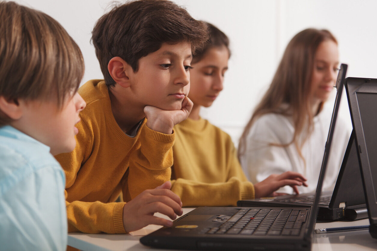 Boy in front of a laptop learning about the foundations of programming during a class with Berlitz Digital School.