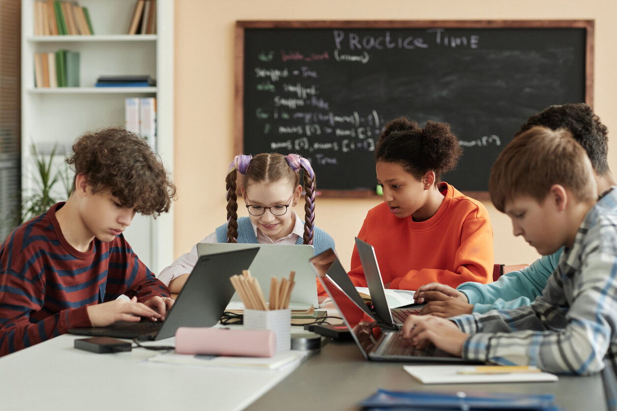 Children in front of their computer learning how to code in Berlitz Digital School's summer camp for kids and teens.