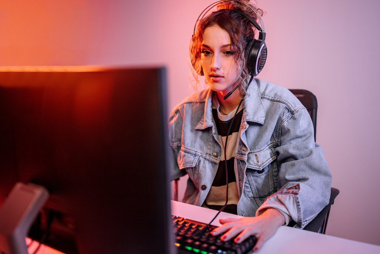 Girl in headphones building a game on her computer after her 3D game development class with Berlitz Digital School.