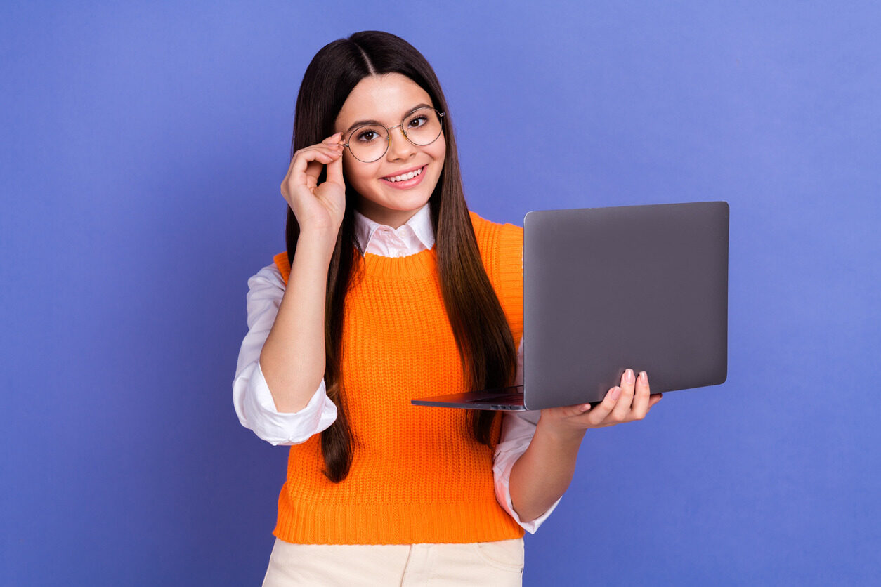 Girl in glasses holding her laptop while learning about programming concepts and logic with Berlitz Digital School's coding classes for kids.