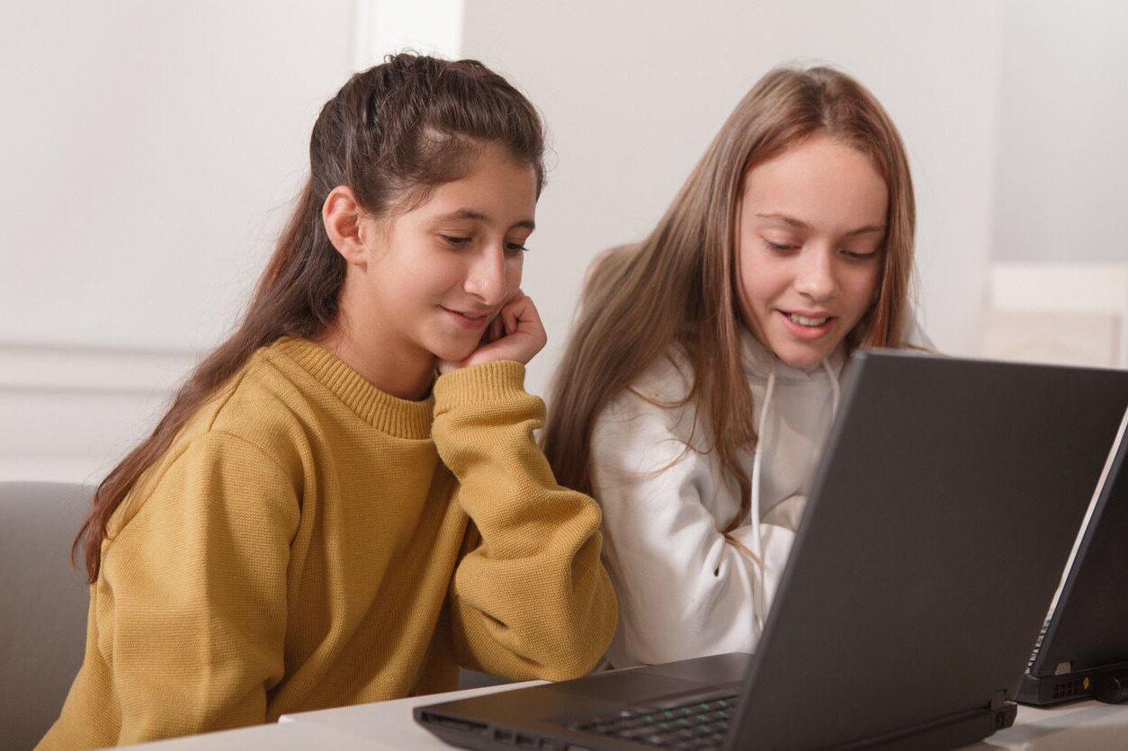 Two girls in front of their laptop learning about entrepreneurship a summar camp with Berlitz Digital School.