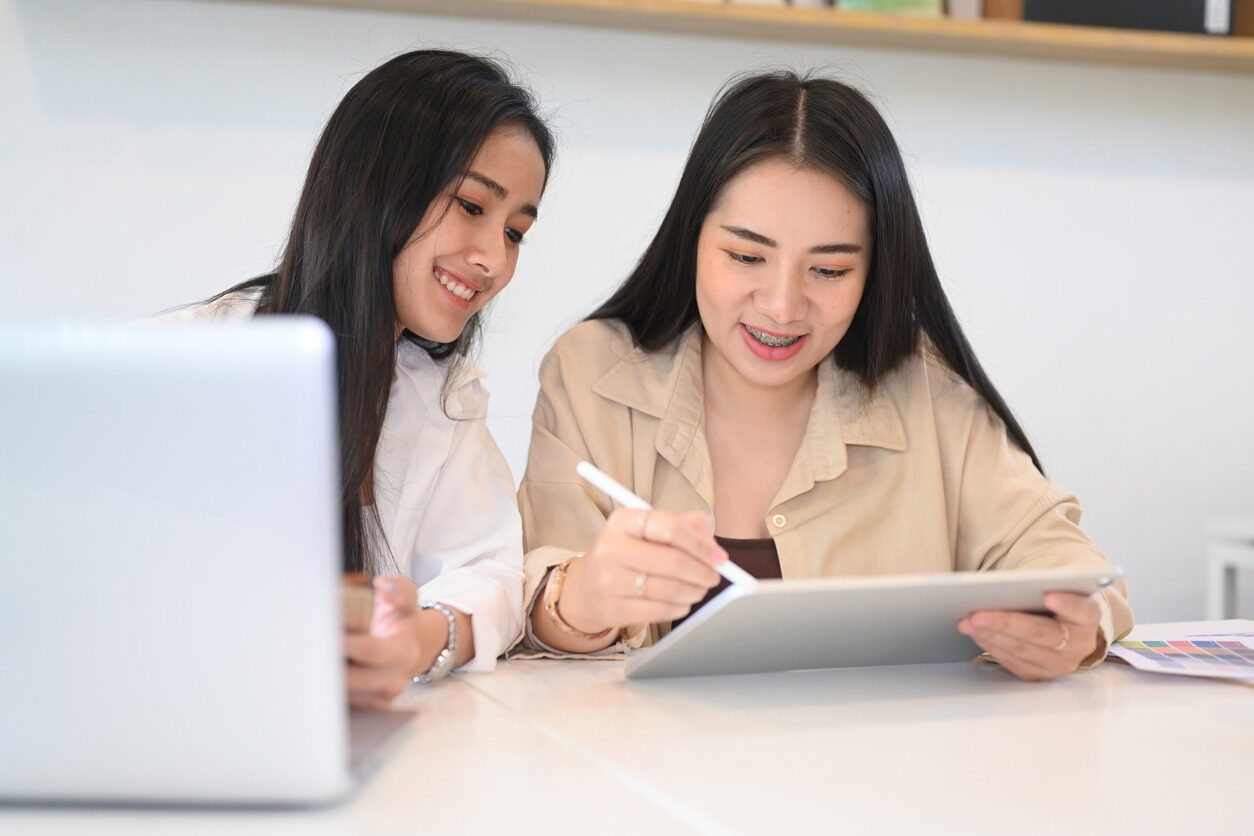 Two girls holding a tablet and learning how manage websites with WordPress.