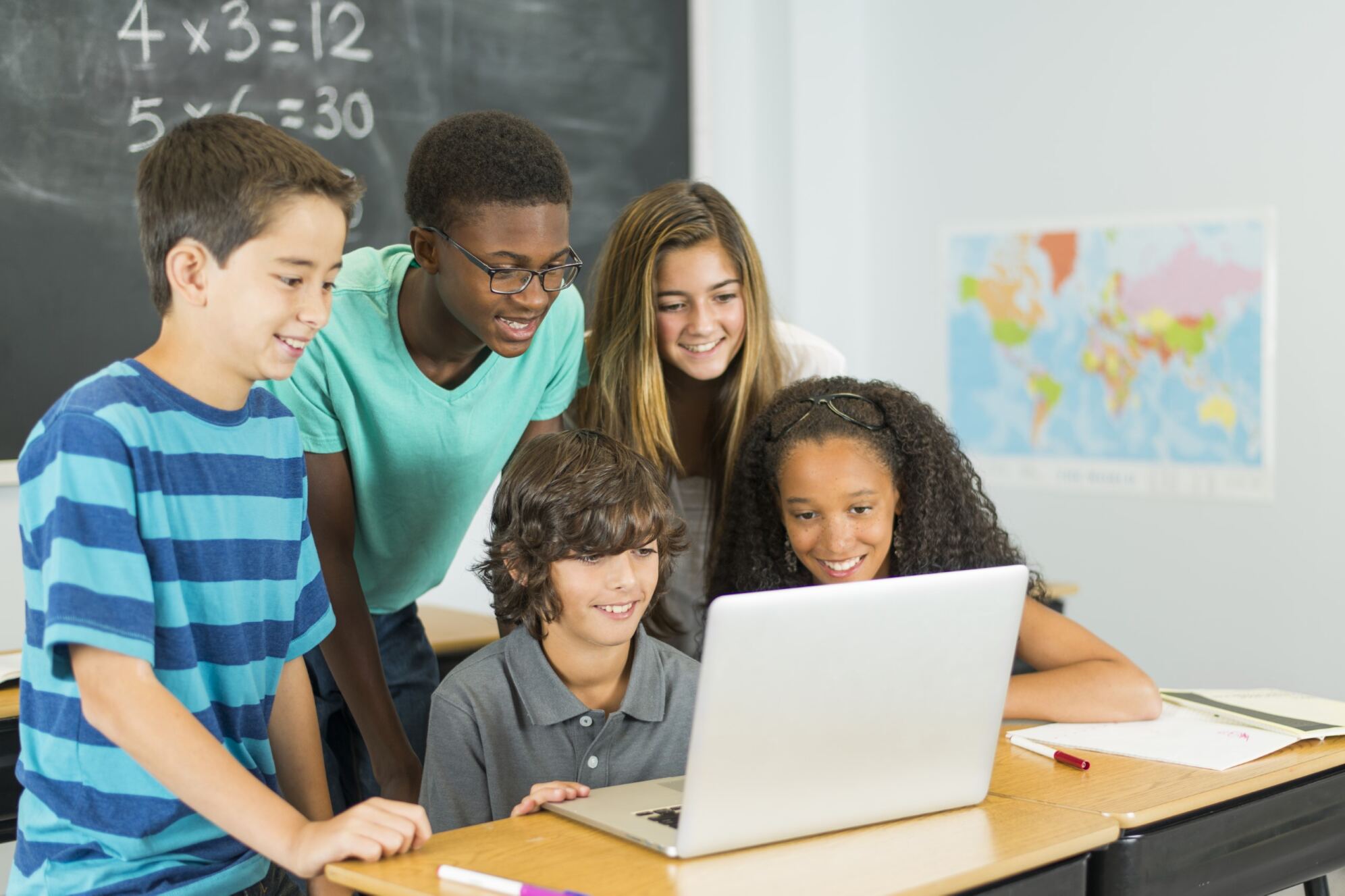 Group of children looking at a computer together and learning about HTML and CSS for kids with Berlitz Digital School.