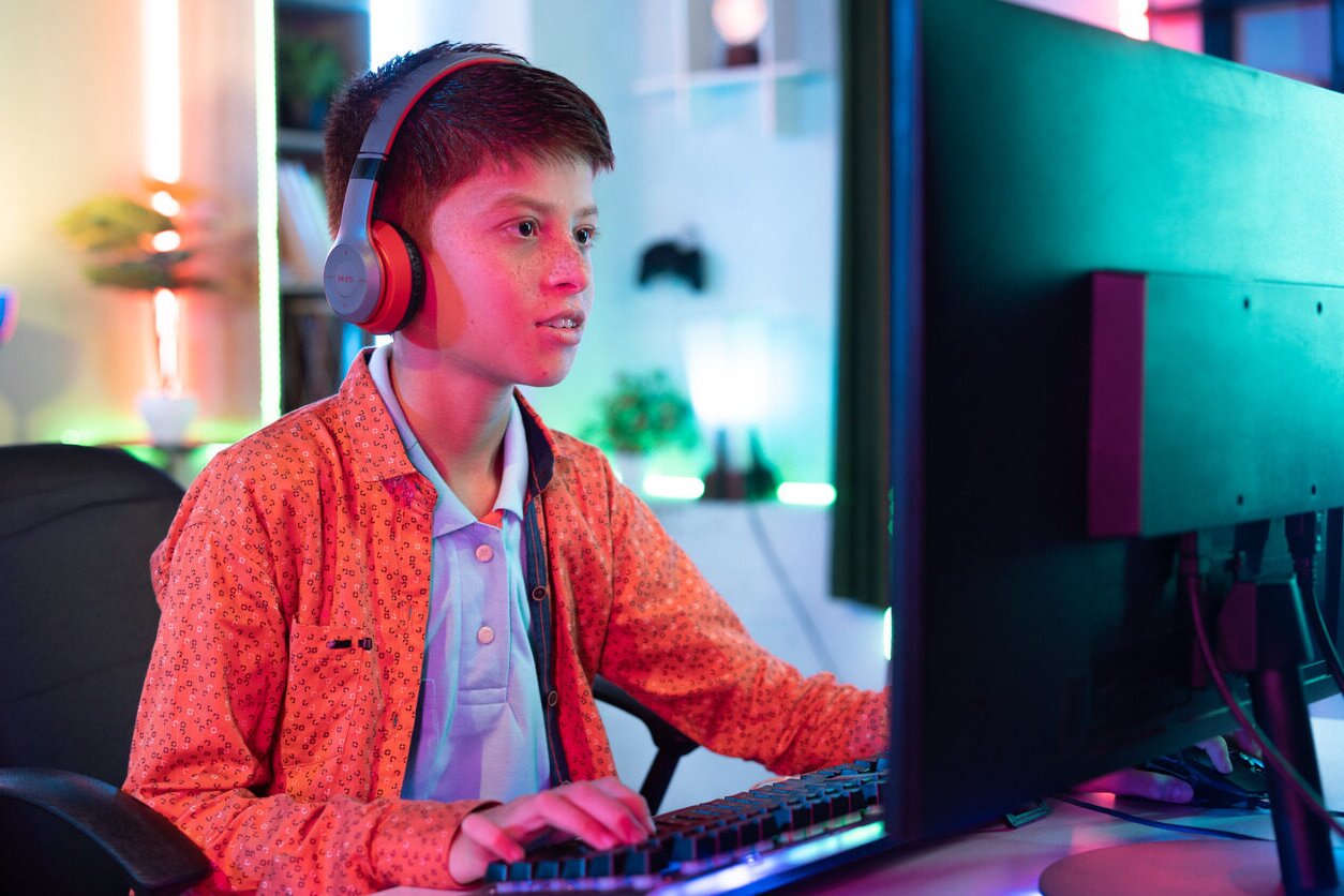 Boy in headphones in front of a computer learn WordPress for kids.