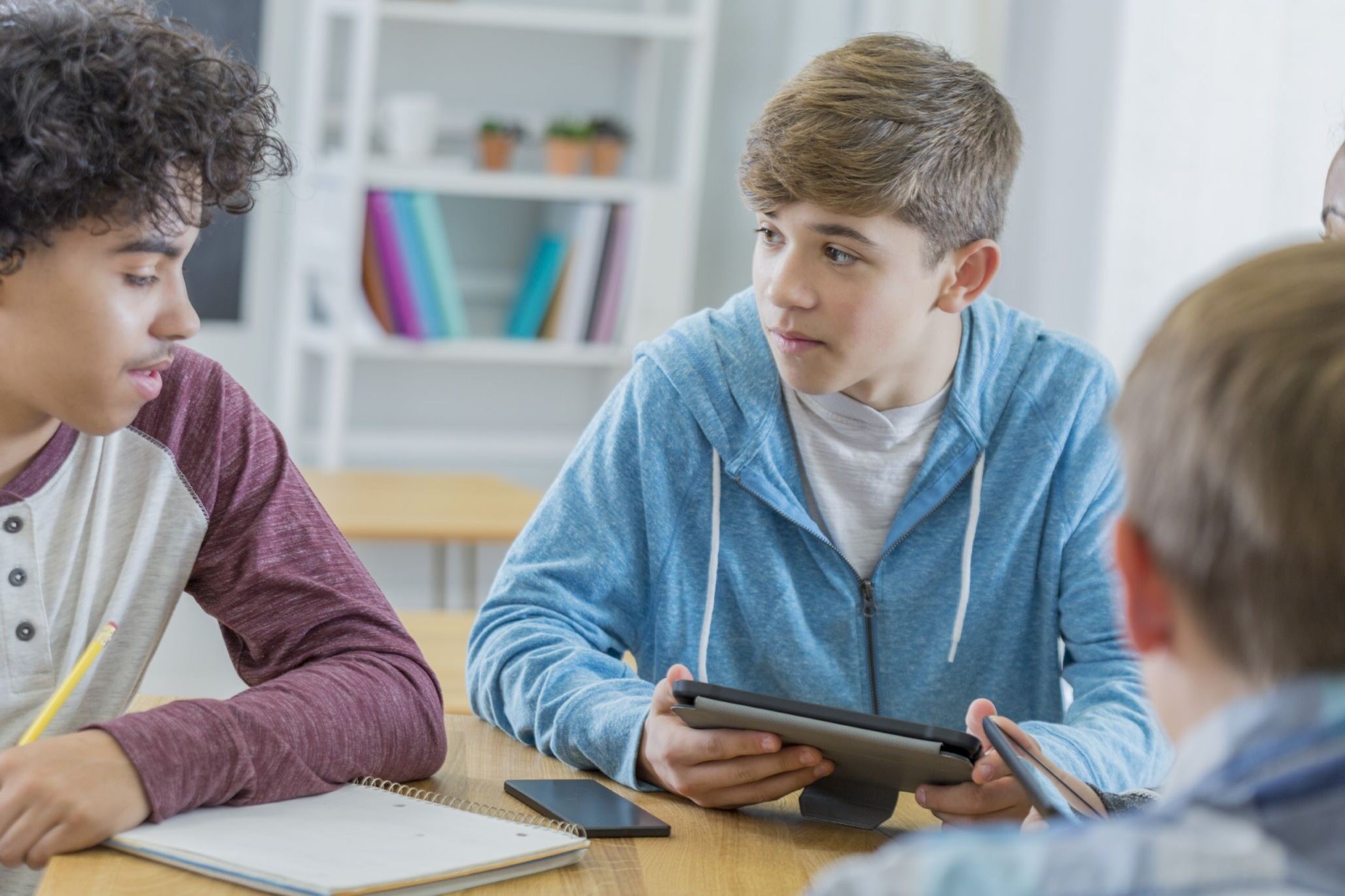 Kids talking to each other during an advanced WordPress class for children with Berlitz Digital School while one of them holds a tablet.