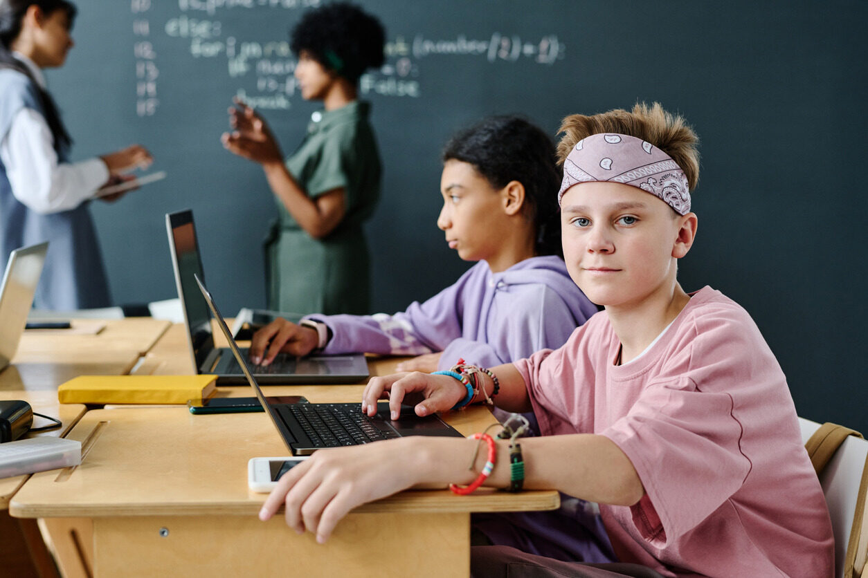 A boy and a girl sitting at a table with their computers and learning about algorithms.