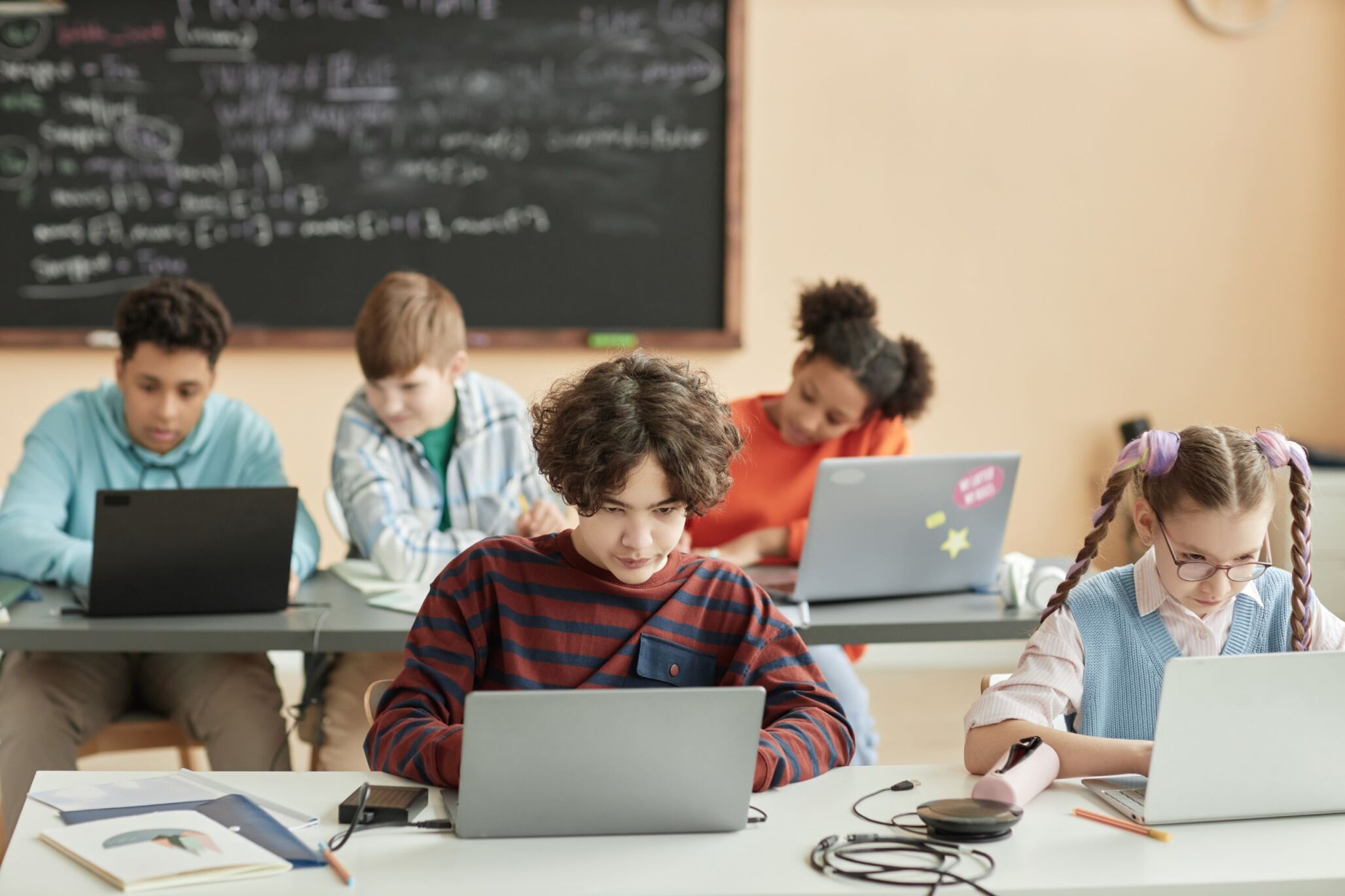 Students typing on their laptops during a coding class for kids and teens with Berlitz Digital School.