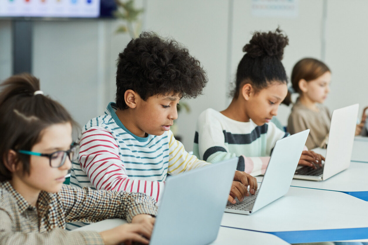 Kids sitting in front of their laptops and learning about coding with Berlitz Digital School's beginner classes for children.